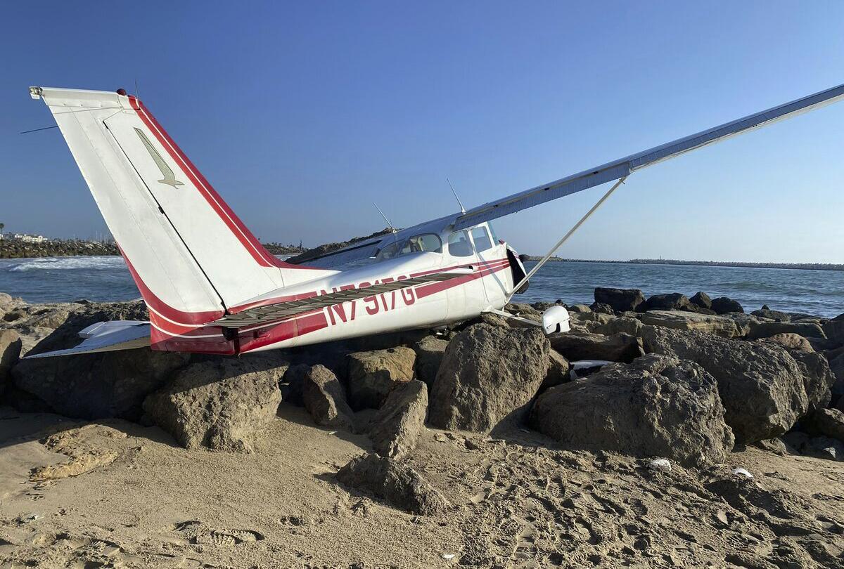 In a photo provided by the Ventura Police Department, a plane lies on the jetty at the beach at Marina Park after a crash Friday, Sept. 16, 2022, in Ventura., Calif. The three occupants escaped unharmed, authorities said. (Ventura Police Department via AP)