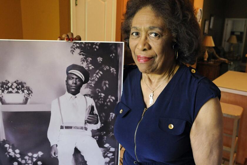 In this Wednesday, April 18, 2018 photo, Josephine Bolling McCall poses with a photo of her father, lynching victim Elmore Bolling, at her home in Montgomery, Ala. Bolling is among thousands of lynching victims remembered at the new National Memorial for Peace and Justice, erected with donations by the Alabama-based Equal Justice Initiative. The memorial and an accompanying museum, which aim to tell the story of racial oppression in the United States, open April 26. (AP Photo/Jay Reeves)