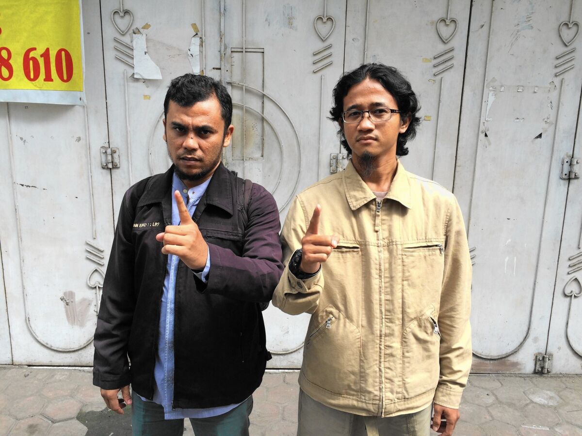 Afrian and Rahmat, both 33, raise their fingers in a salute to Islamic State.
