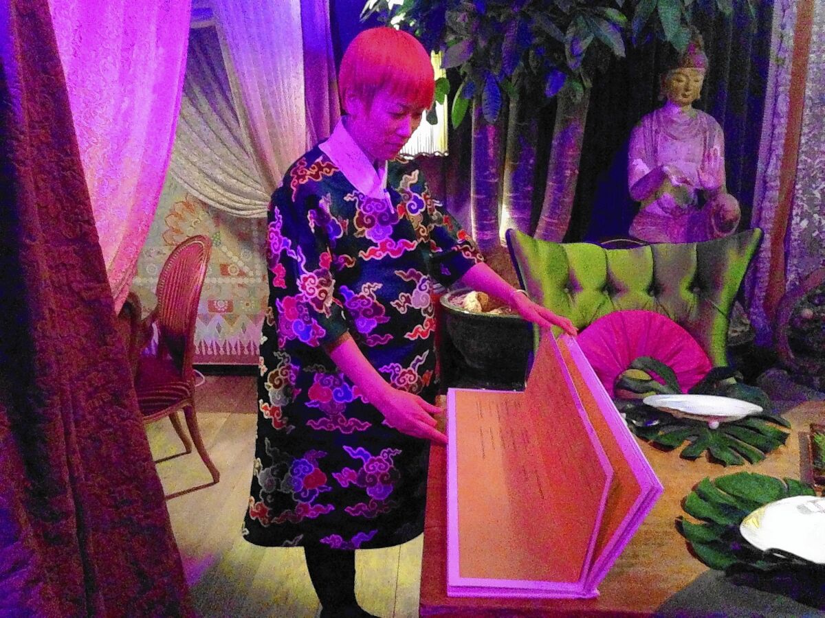 An employee at Beijing's Pure Lotus restaurant displays the menu, which is 2 1/2 feet wide and weighs 4 pounds, 5 ounces. The restaurant also offers a nine-course, $133 tasting menu, which is carved into an inch-thick wooden plank, also 2 1/2 feet wide.