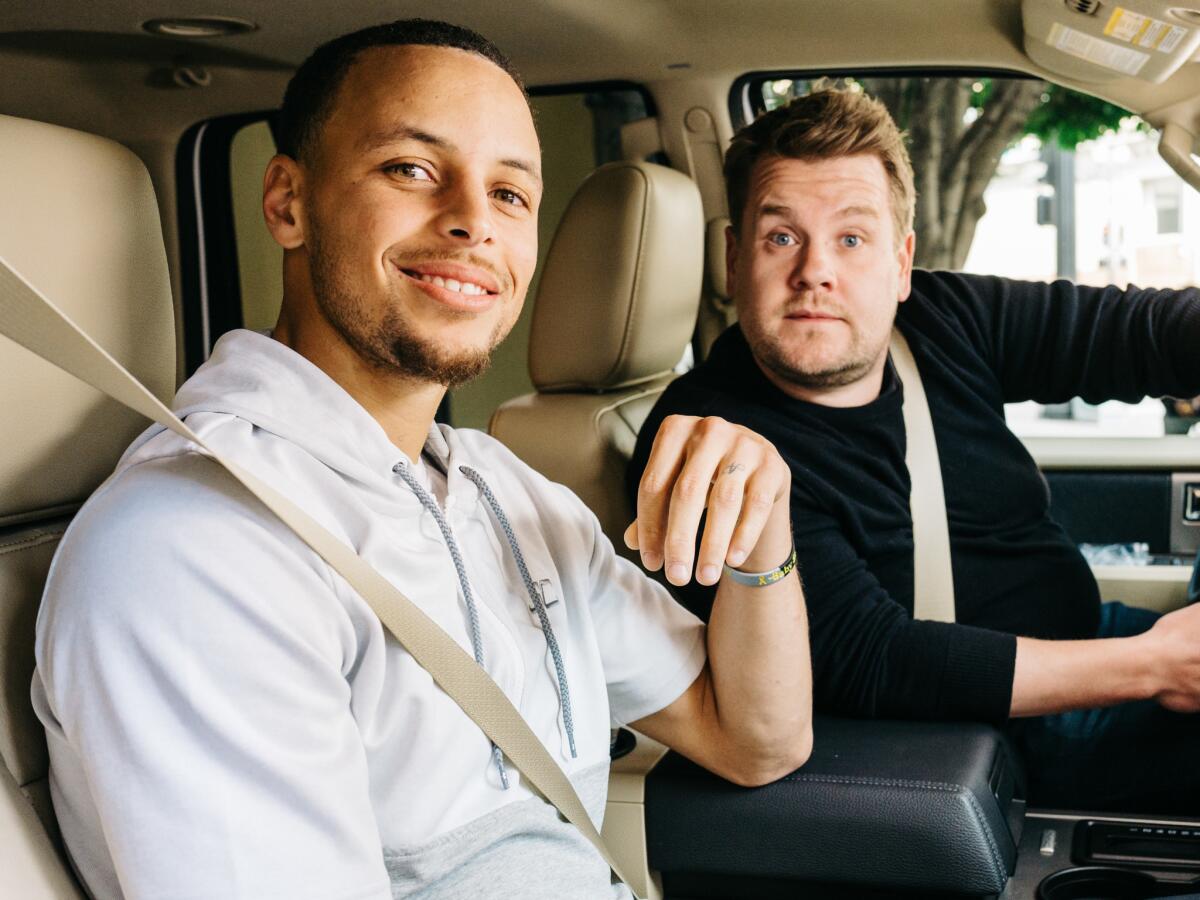 Stephen Curry and James Corden seated in a car.