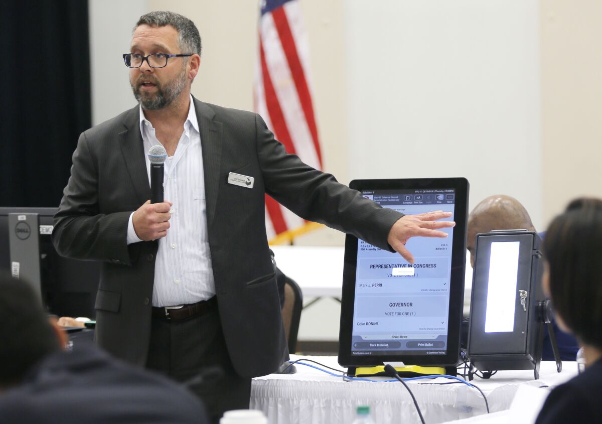 FILE - In this Aug. 30, 2018 file photo, Eric Coomer from Dominion Voting demonstrates his company's touch screen tablet that includes a paper audit trail at the second meeting of Secretary of State Brian Kemp's Secure, Accessible & Fair Elections Commission in Grovetown, Ga. Attorneys for President Donald Trump’s re-election campaign, its onetime attorney Rudy Giuliani and conservative media figures asked a judge Wednesday, Oct. 13, 2021, to dismiss a defamation lawsuit by Coomer, a former employee of Dominion Voting Systems, who argues he lost his job after being named in false charges as trying to rig the 2020 election. (Bob Andres/Atlanta Journal-Constitution via AP, File)