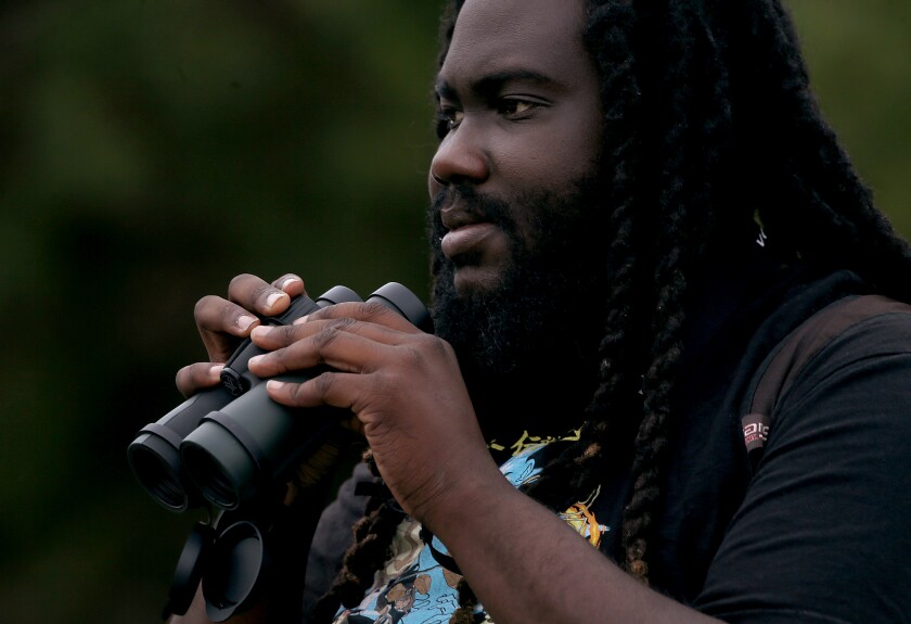 Brian Young looks into the distance while holding binoculars.
