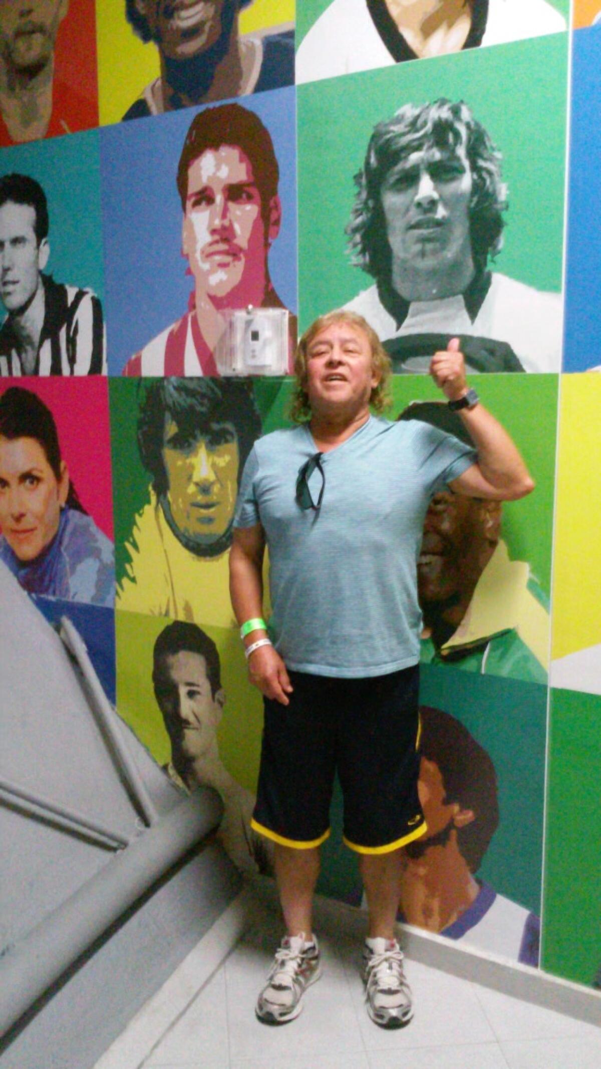 Isauro Sánchez Torres poses in front of a wall with pictures of famous soccer players
