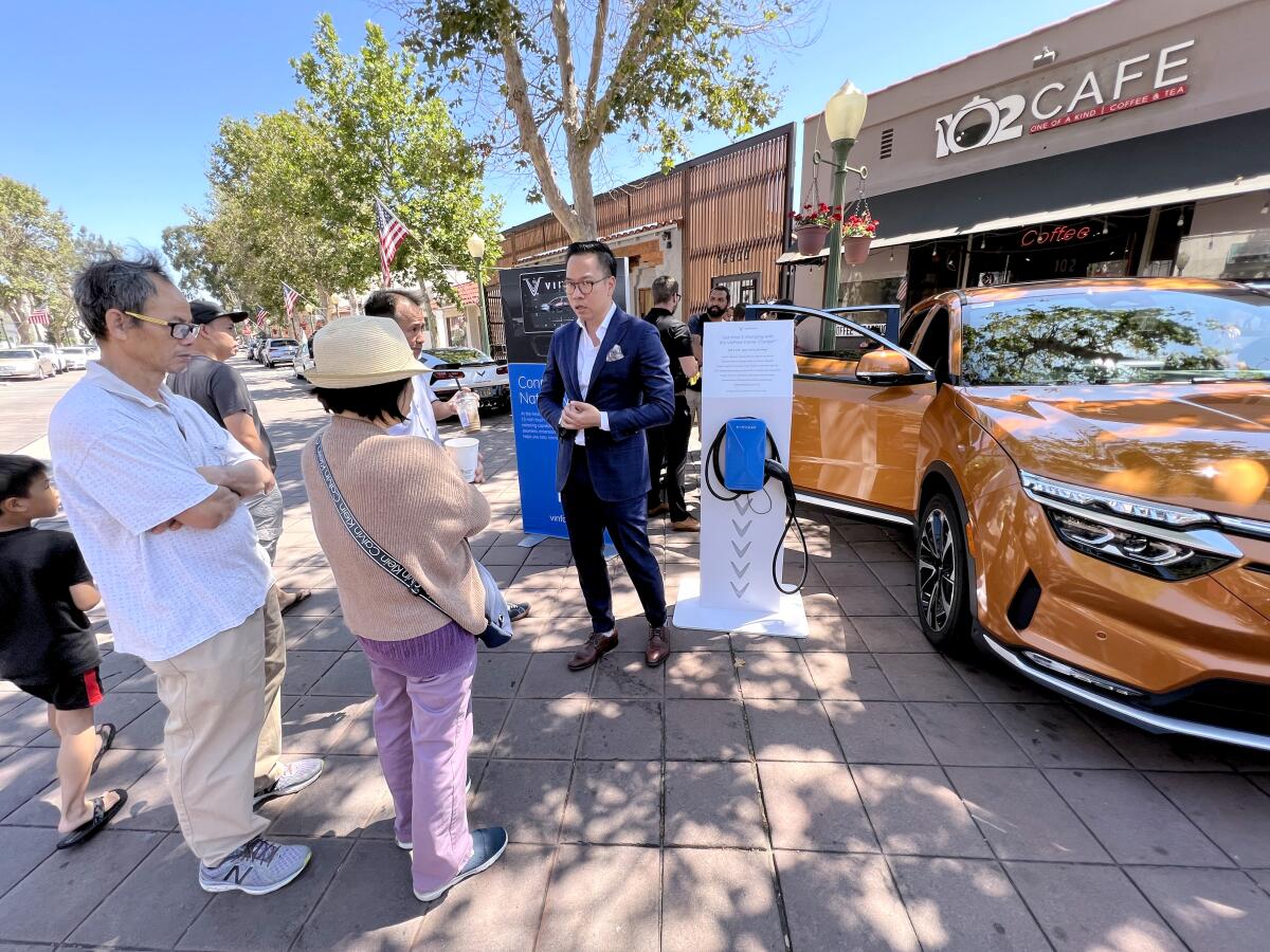 VinFast U.S. sales director Henry Vo, right, talks about the EV charger for the VinFast VF8 electric SUV.