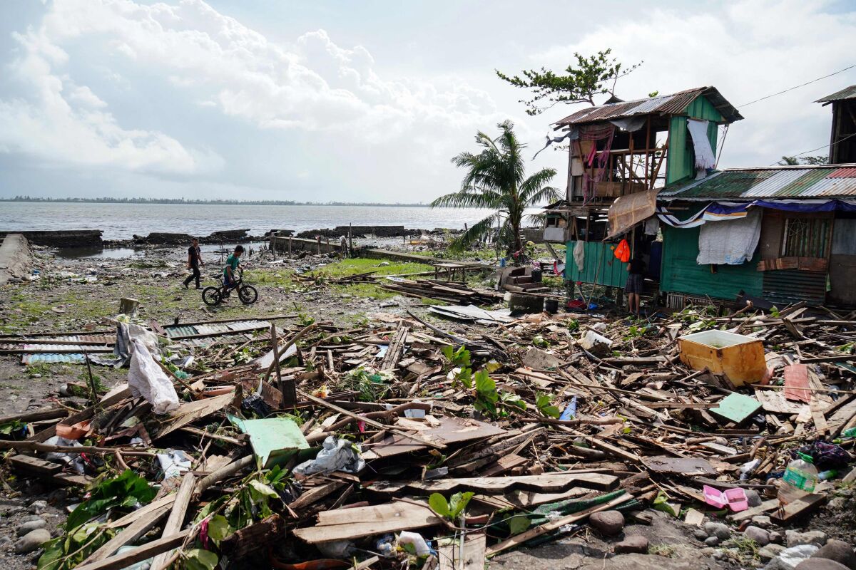 Residents walk past a house damaged during Typhoon Phanfone in Tacloban, Leyte province in the central Philippines.