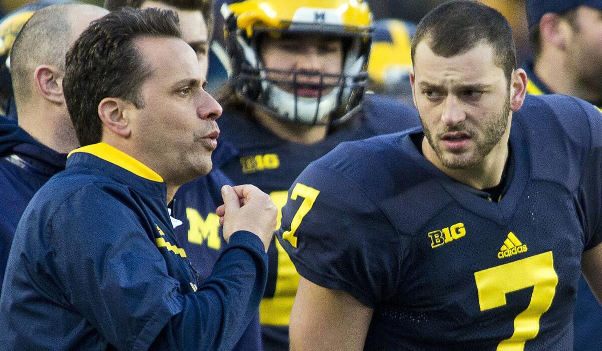 Jedd Fisch, left, sends signals to the field next to quarterback Shane Morris during Michigan's spring game on April 1.