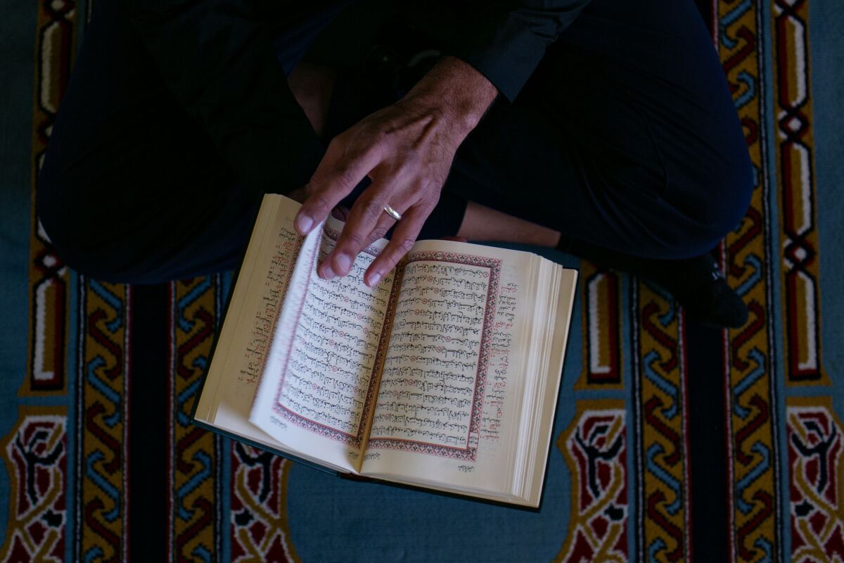 A hand turns the page of a copy of the Quran