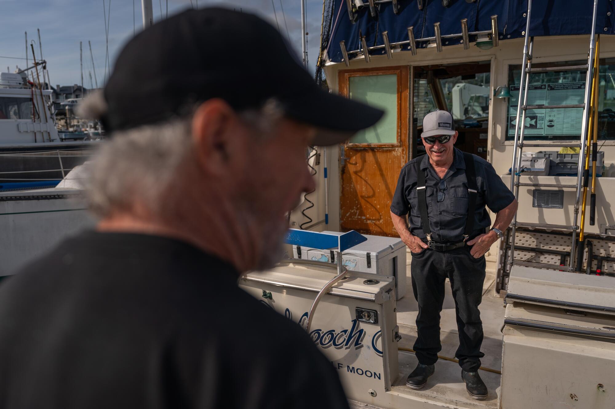 Duane Winter stands on his boat and chats with Chris Pedersen on the docks.