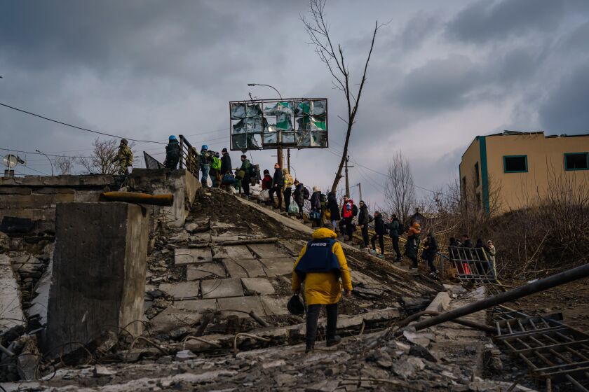 IRPIN, UKRAINE -- MARCH 4, 2022: Civilians cross the Irpin river through the rubble of a destroyed bridge to escape the fighting between Russian and Ukrainian forces drawing closer to Irpin, Ukraine, Friday, March 4, 2022. (MARCUS YAM / LOS ANGELES TIMES)