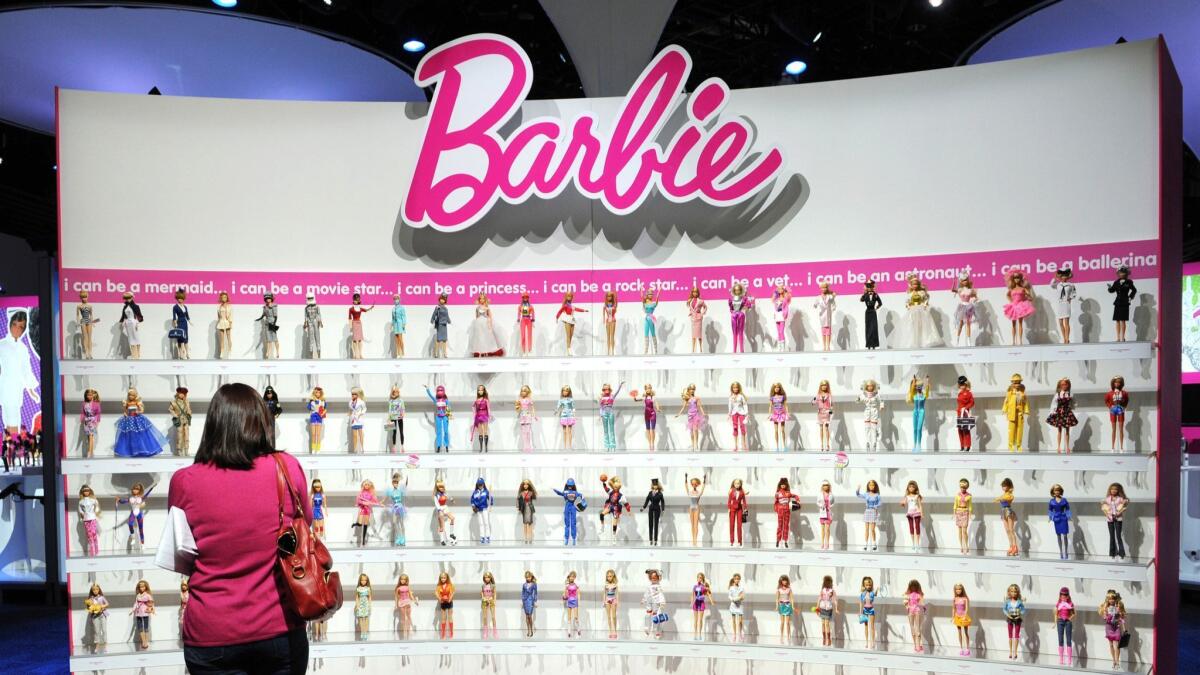 A woman photographs a wall of Barbie dolls in the Mattel display at the 2010 Toy Fair in New York.