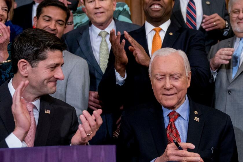 Speaker of the House Paul Ryan, R-Wis., bottom left, and other Republican congressmen, applaud as Senate Finance Committee Chairman Orrin Hatch, R-Utah, seated at center, signs the final version of the GOP tax bill during an enrollment ceremony at the Capitol in Washington, Thursday, Dec. 21, 2017. (AP Photo/Andrew Harnik)