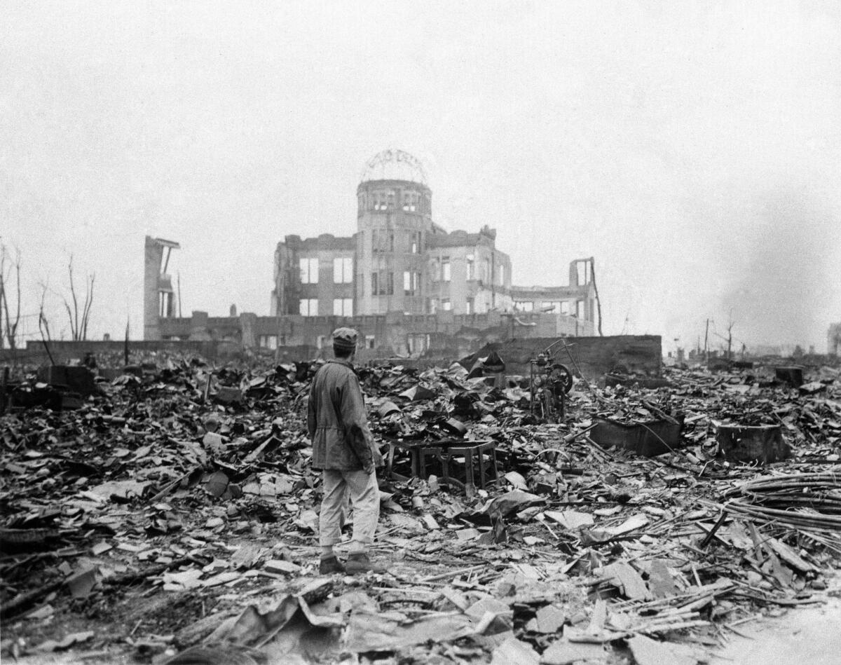 In this Sept. 8, 1945 file photo, an allied correspondent stands in the rubble in front of the shell of a building that once was a movie theater in Hiroshima, Japan, a month after the first atomic bomb ever used in warfare was dropped by the U.S.