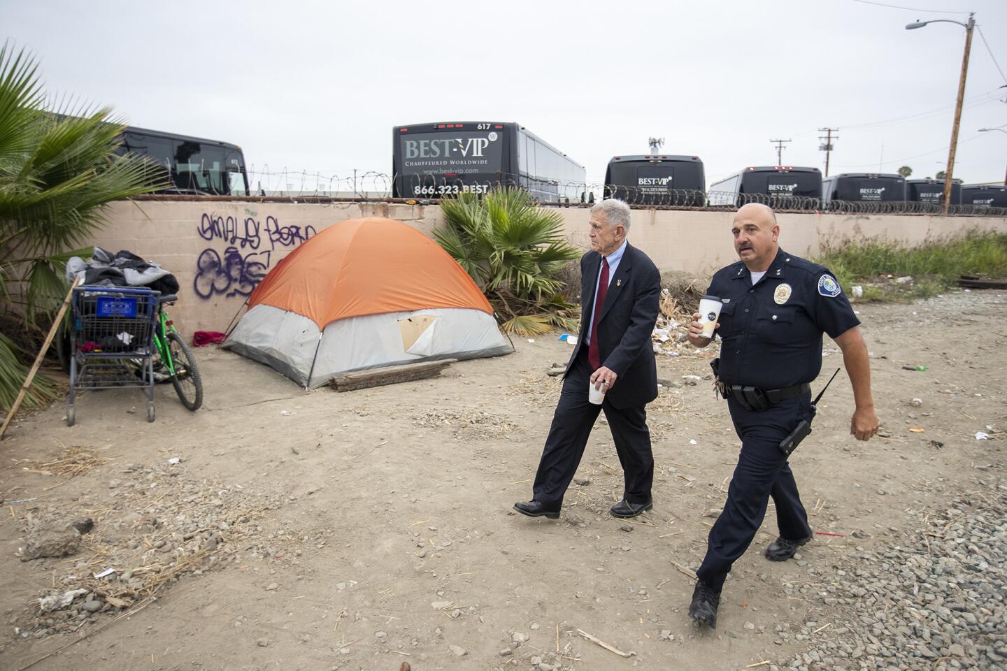 U.S. District Judge David Carter and Santa Ana police Acting Deputy Chief Ken Gominsky walk past a tent along railroad tracks near Goetz Avenue and Main Street in Santa Ana on Tuesday, June 5.