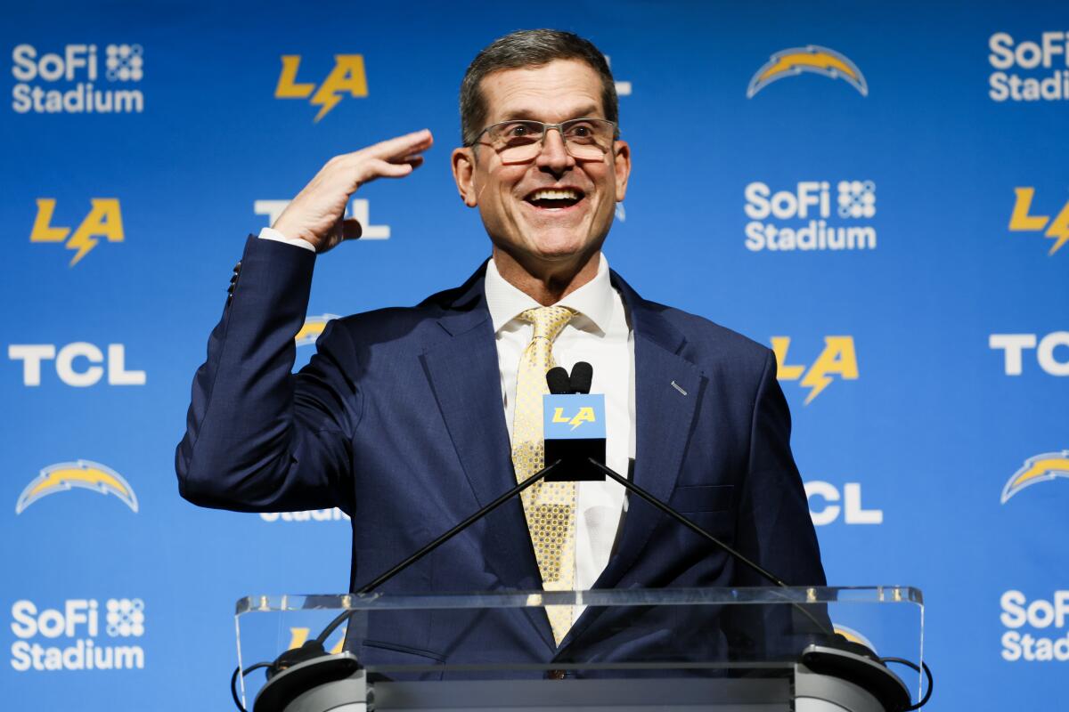 Chargers coach Jim Harbaugh gestures toward his head during his introductory news conference.