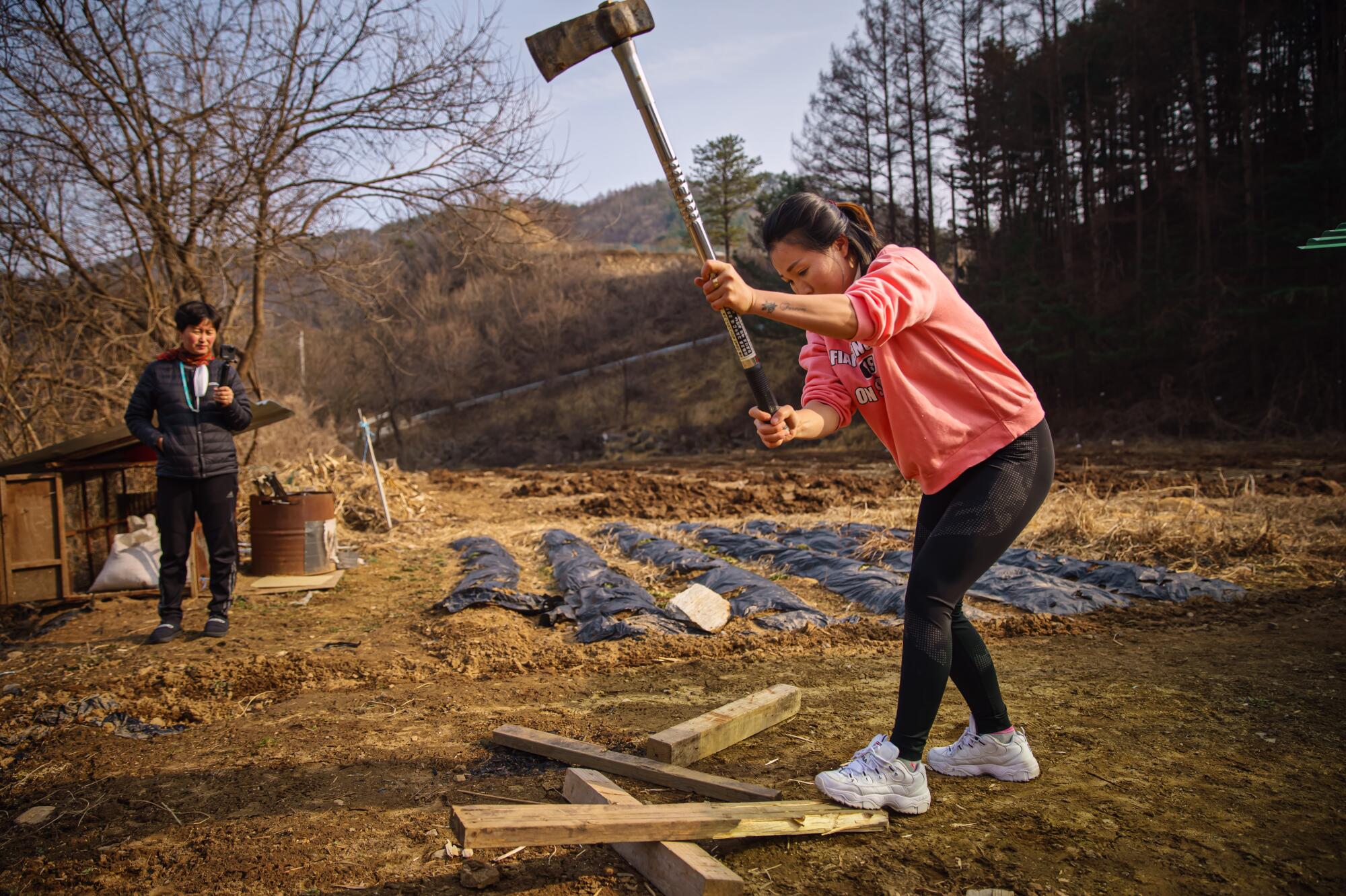 A woman chops firewood in front of a camera