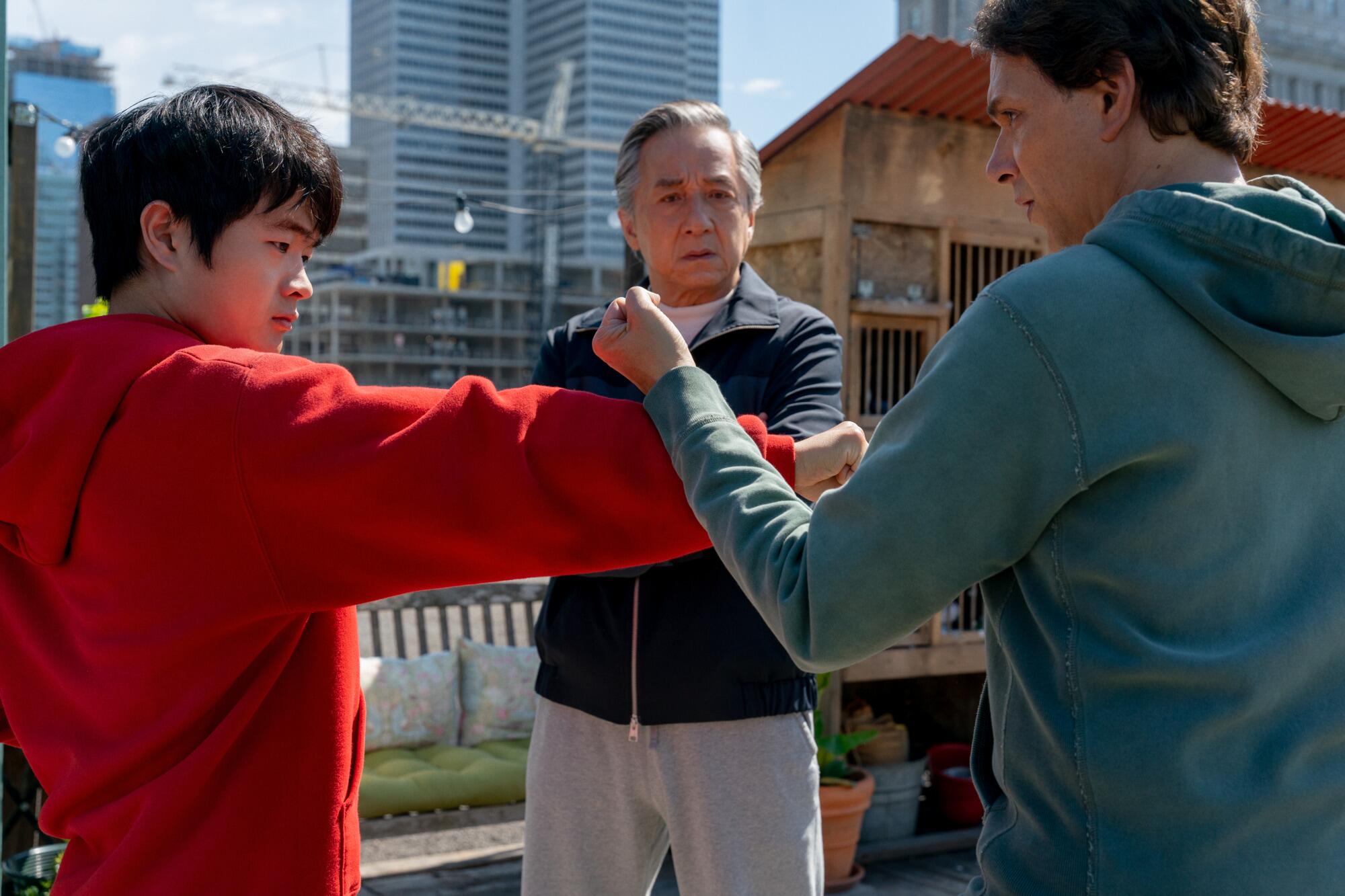 Three men practice martial arts on a rooftop.
