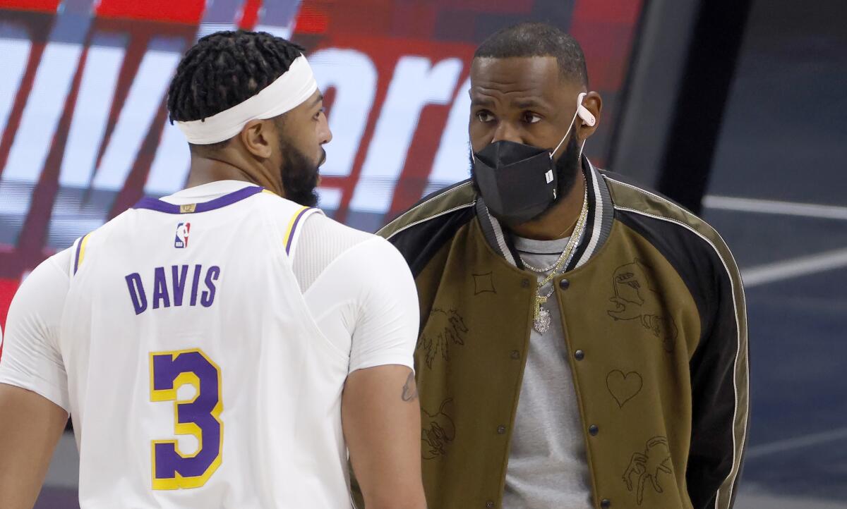 The Lakers' Anthony Davis and LeBron James, who is out with an injury, talk during a timeout April 24, 2021.