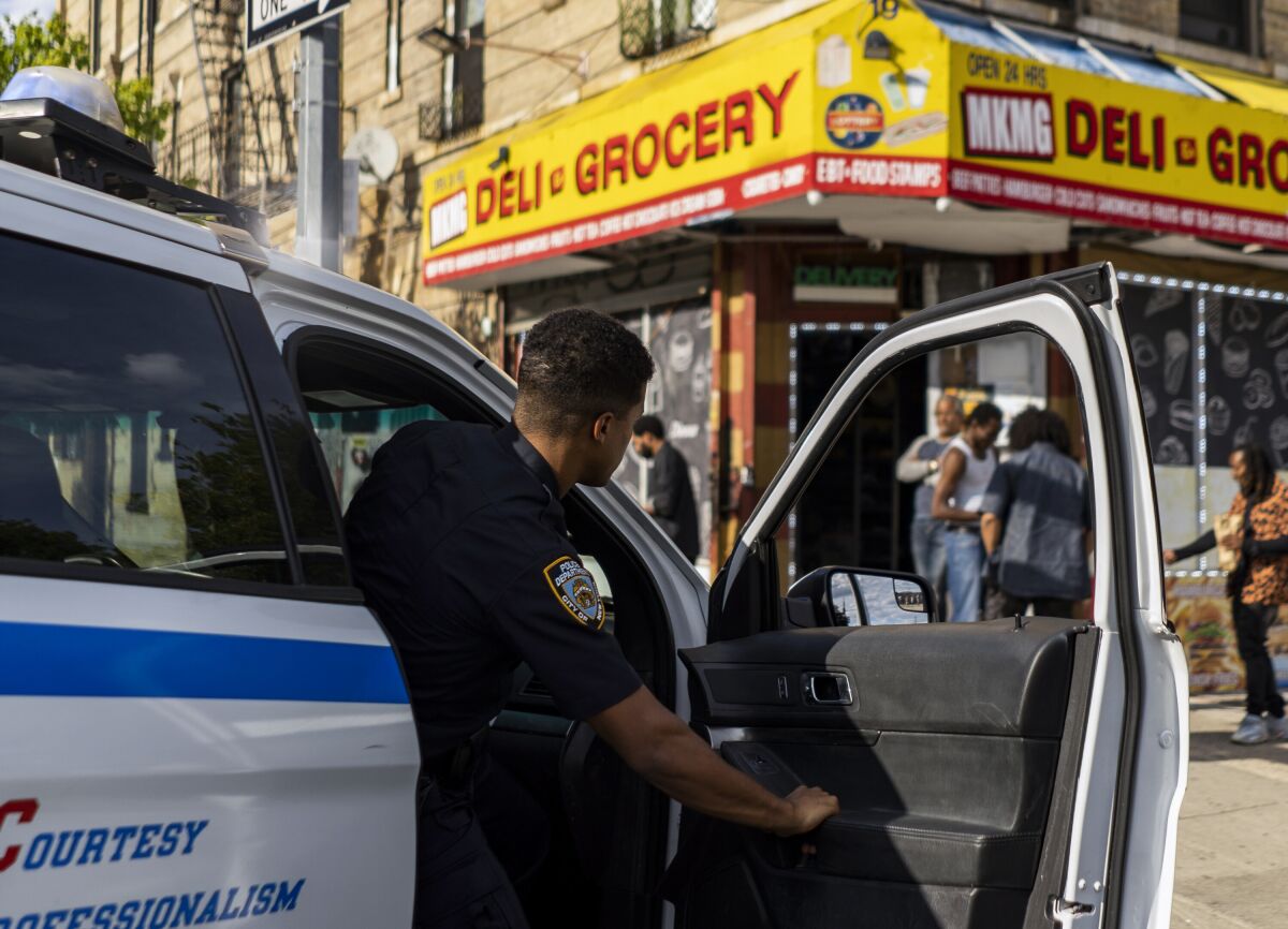 A police officer gets out of a patrol car outside a New York deli.