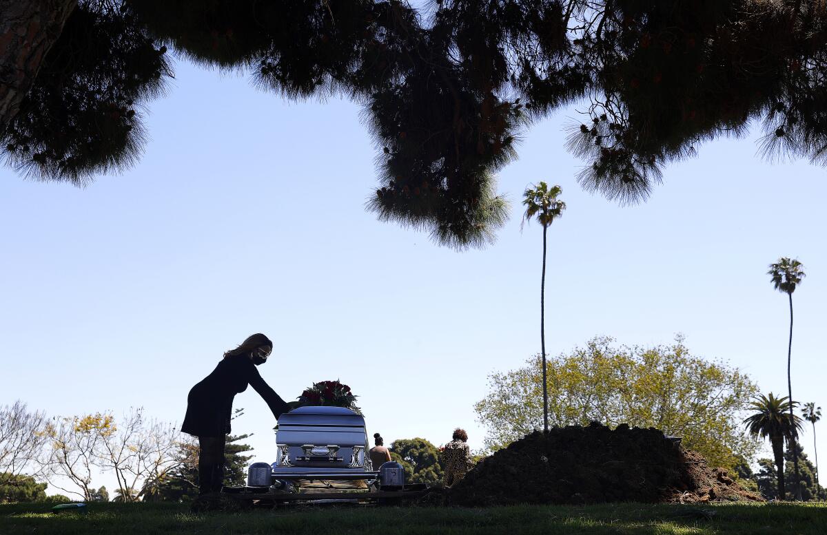 Clarice Kavanaugh places a hand on the casket of her friend Charles Jackson at Inglewood Park Cemetery on April 15. 