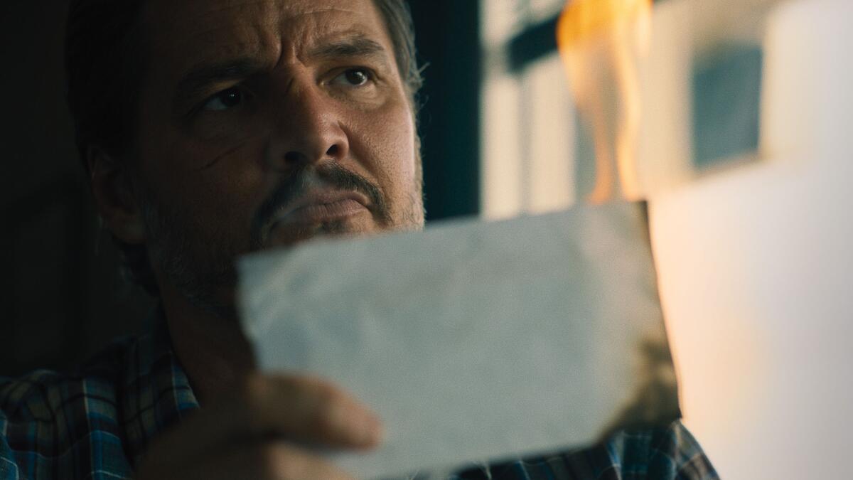 A man holds up a burning piece of paper.