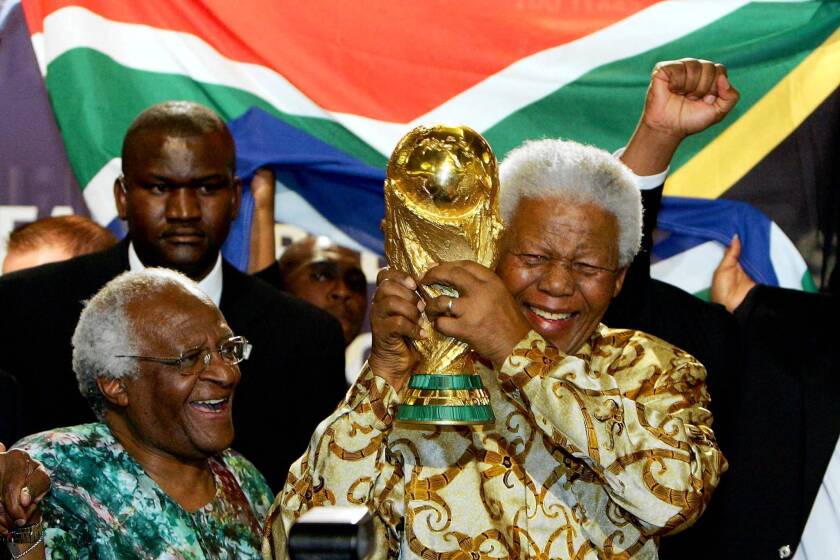 Former South African President Nelson Mandela holds the Jules Rimet World Cup beside Capetown Archbishop Desmond Tutu at the FIFA headquarters in Zurich.
