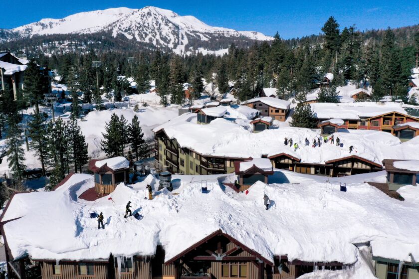 An aerial image shows workers removing snow from rooftops after record snowfall from winter storms in Mammoth Lakes, California on April 6, 2023. (Photo by Patrick T. Fallon / AFP) (Photo by PATRICK T. FALLON/AFP via Getty Images)