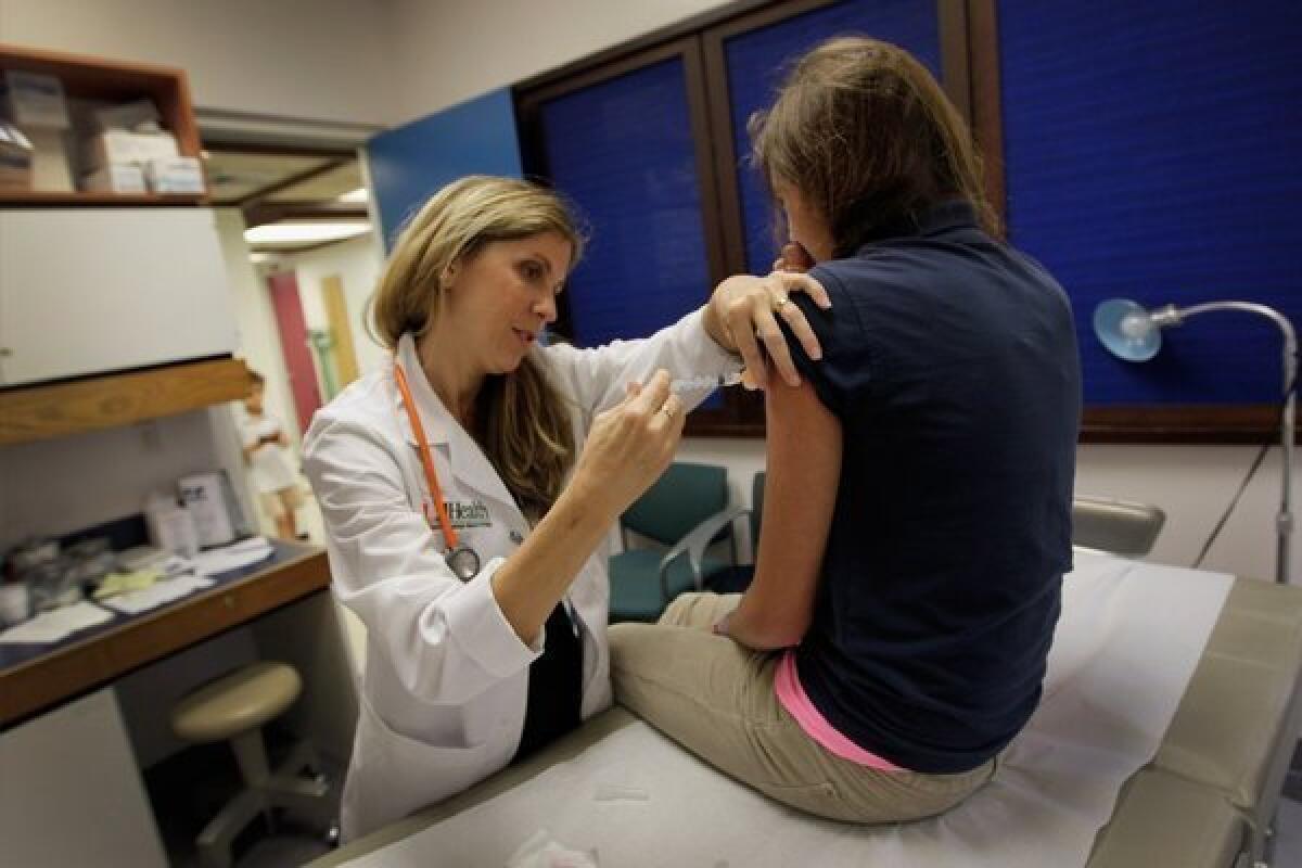 A teenage girl receives a vaccination against the human papilloma virus, or HPV, from University of Miami pediatrician Dr. Judith L. Schaechter.