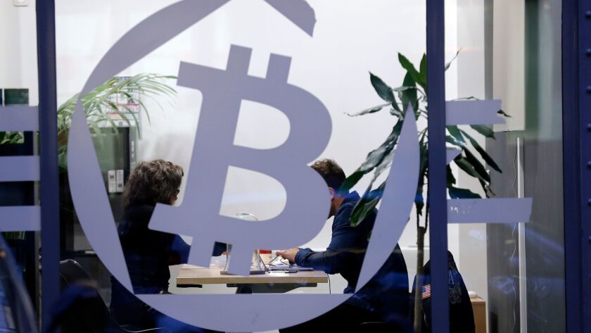 A bitcoin symbol is displayed on a window of the offices of the bank La Maison du Bitcoin in Paris. The value of the digital cryptocurrency bitcoin soared past $16,000 on Thursday.