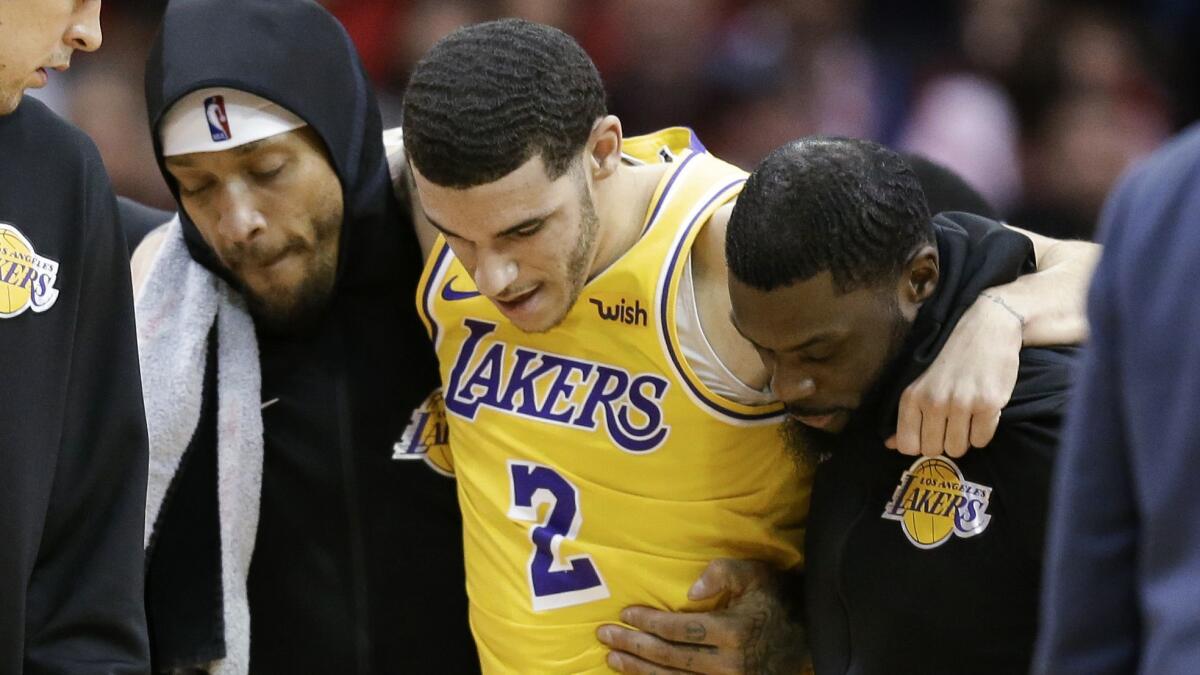 Lakers guard Lonzo Ball, being helped off the court by teammates Michael Beasley, left, and Lance Stephenson after suffering an injury Jan. 19 against Houston, has been sidelined for the rest of the season.