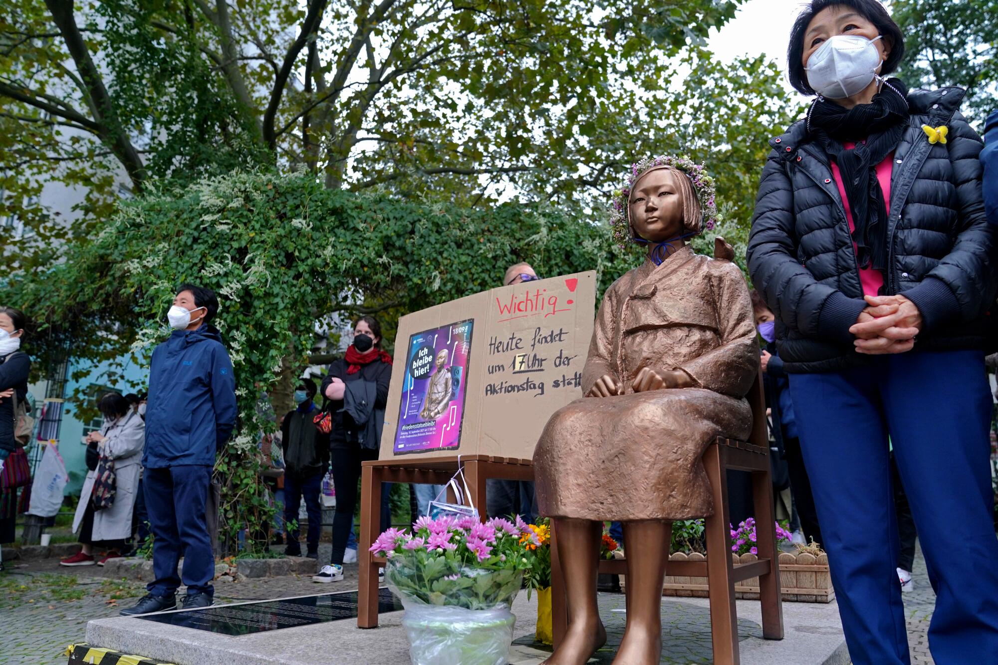 People stand beside the "comfort women" memorial in Berlin