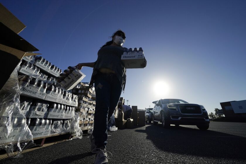 Volunteers distribute food to people who waited in line in their cars overnight, at a food distribution point in Metairie, La., Thursday, Nov. 19, 2020. (AP Photo/Gerald Herbert)