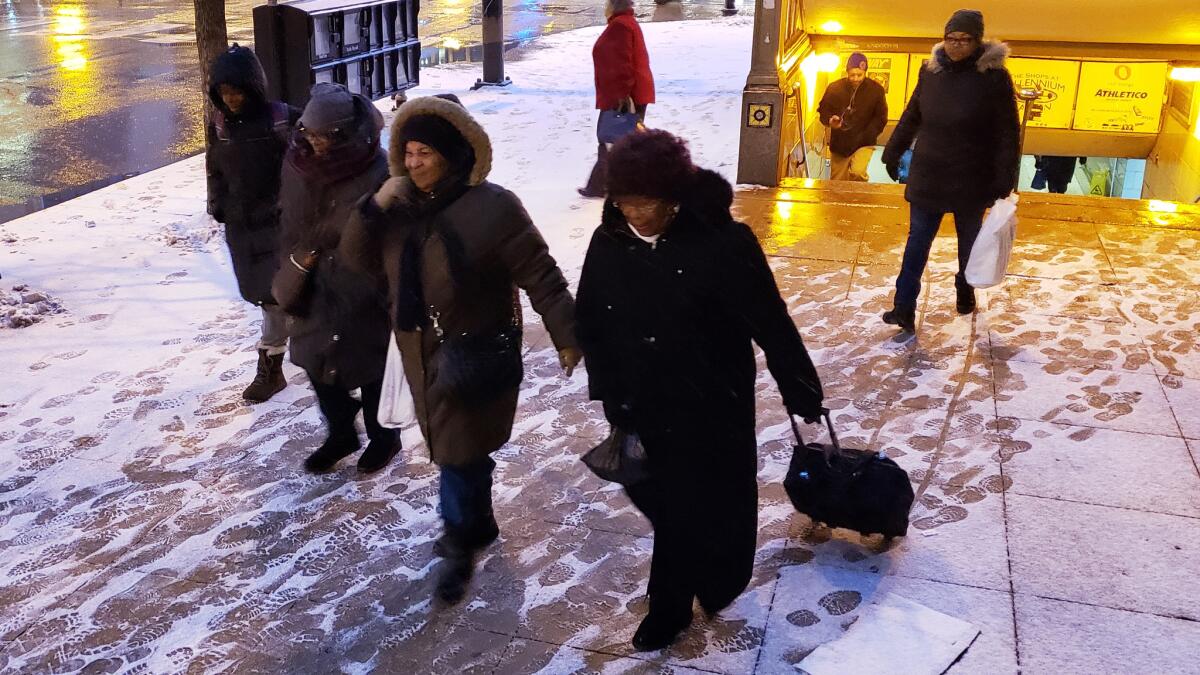 People emerge from Millennium Station into sleet and wind swirling about Randolph Street in Chicago on Wednesday.