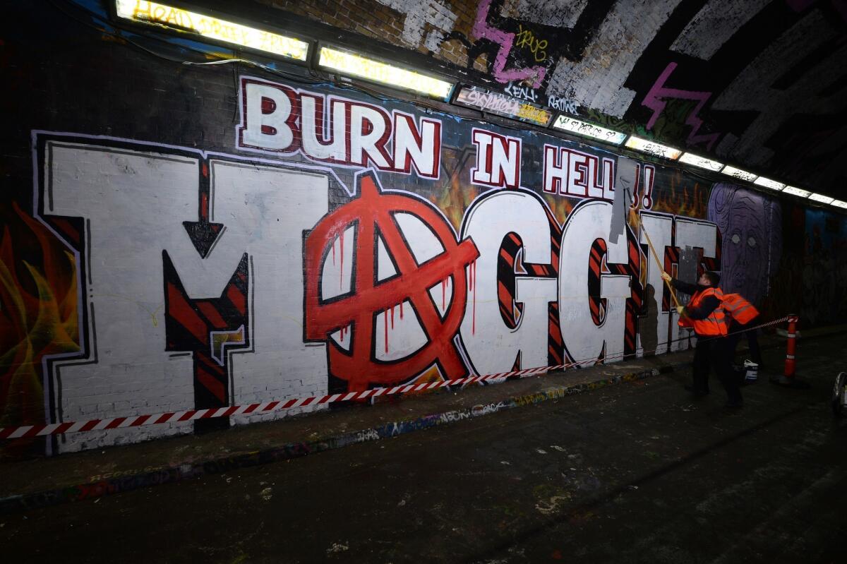 Workers paint over grafitti that reads "Burn in hell Maggie," referring to Britain's late ex-Prime Minister Margaret Thatcher, in London on Friday.