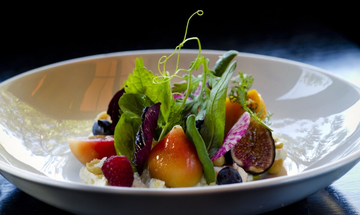 A colorful dish of beets and sliced berries decorated with fronds, tendrils and leaves by chef Chris Jacobson.