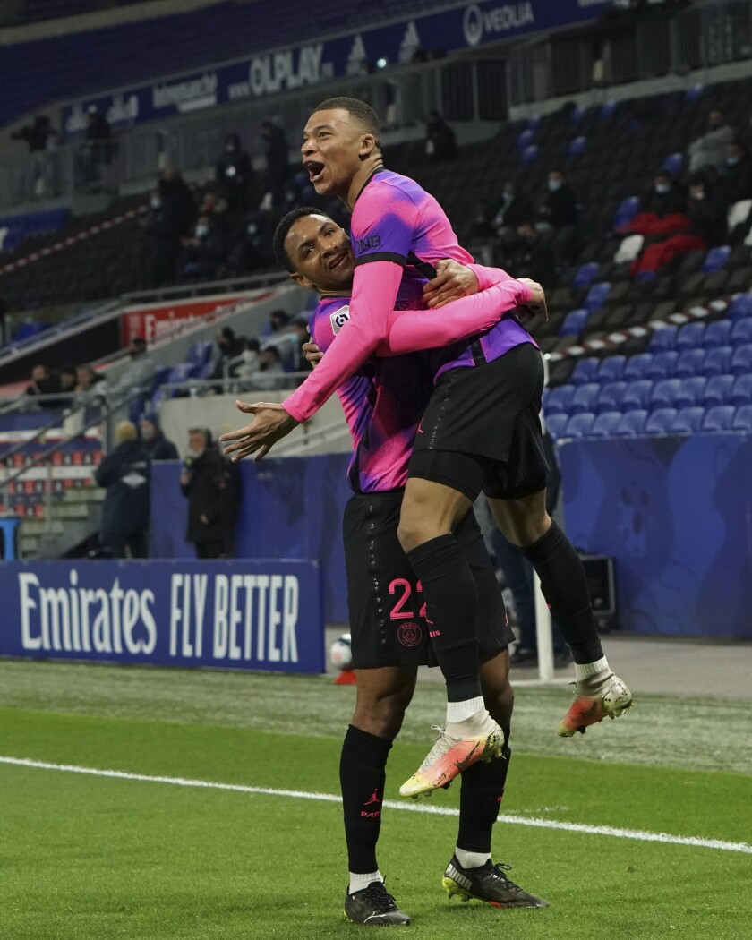 Paris Saint Germain's Kylian Mbappe, right, celebrates with Abdou Diallo after he scored a goal against Lyon during the French League One soccer match between Lyon and PSG in Decines, near Lyon, central France, Sunday, March 21, 2021. (AP Photo/Laurent Cipriani)