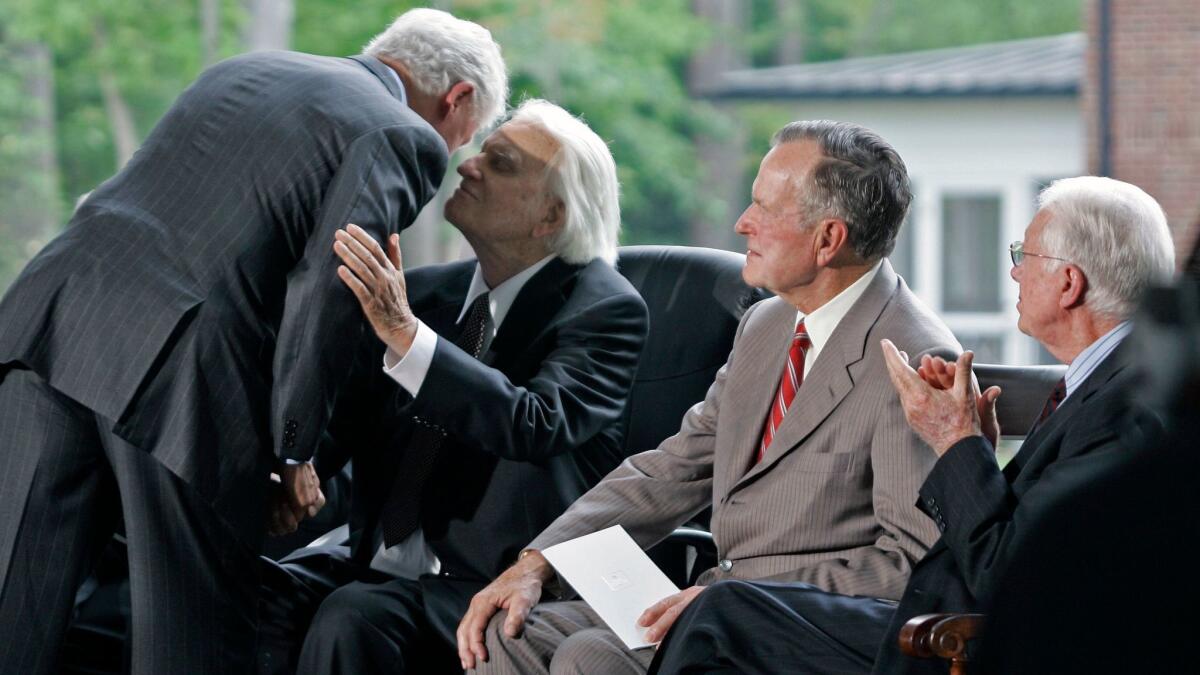Former President Clinton, left, embraces Billy Graham as former Presidents George H.W. Bush, second from right, and Jimmy Carter look on during the 2007 dedication for the Billy Graham Library in Charlotte, N.C.,