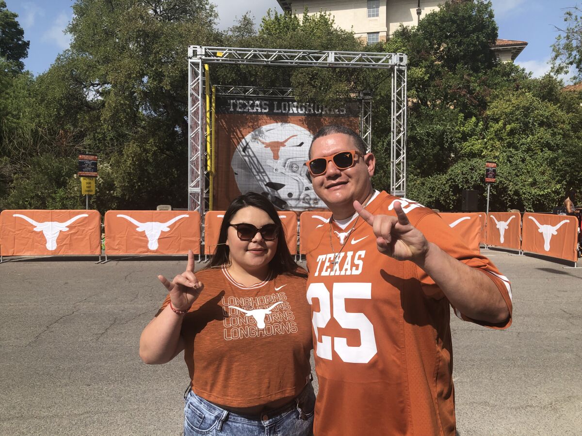 Orlando Candelaria and friend Evelyn Salcedo gesture horn signs while wearing Longhorns shirts.