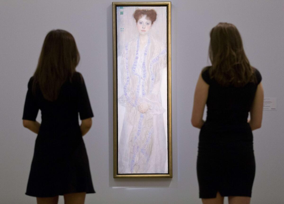 Two employees of Sotheby's auction house pose by a portrait of Gertrud Loew (Gertha Felsovanyi) by Austrian artist Gustav Klimt painted in 1902.