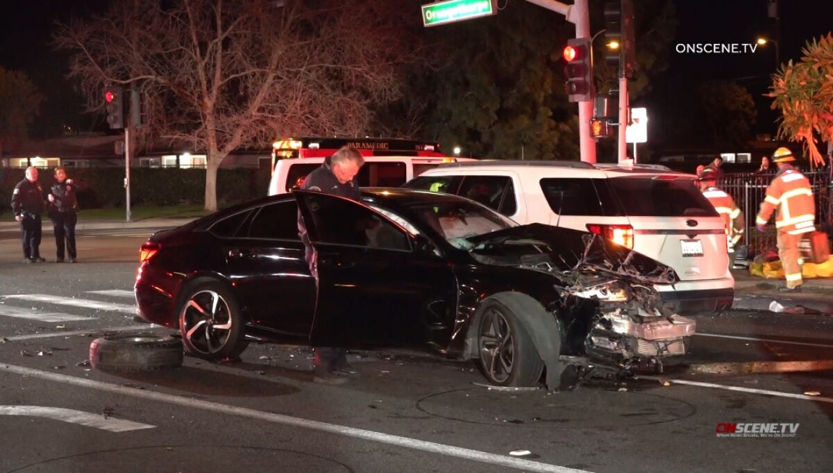A police officer stands next to a wrecked sedan in an intersection