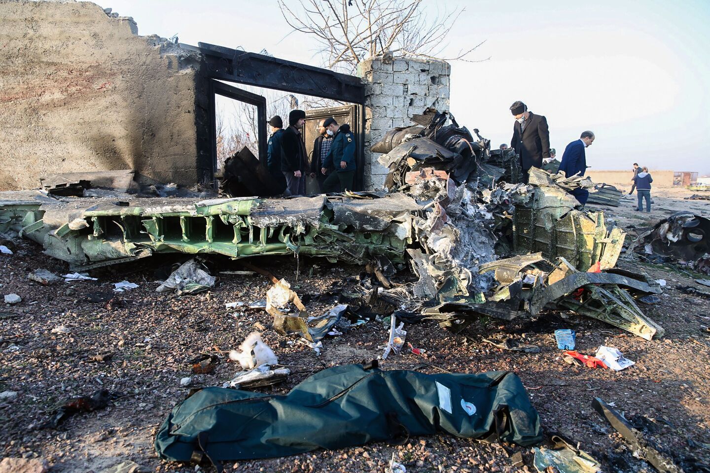 People stand near the wreckage after a Ukrainian plane carrying 176 passengers crashed near Imam Khomeini airport in Tehran on January 8, 2020. - All 176 people on board a Ukrainian passenger plane were killed when it crashed shortly after taking off from Tehran on January 8, Iranian state media reported. State news agency IRNA said 167 passengers and nine crew members were on board the aircraft operated by Ukraine International Airlines. (Photo by ROHHOLLAH VADATI / ISNA / AFP) (Photo by ROHHOLLAH VADATI/ISNA/AFP via Getty Images)
