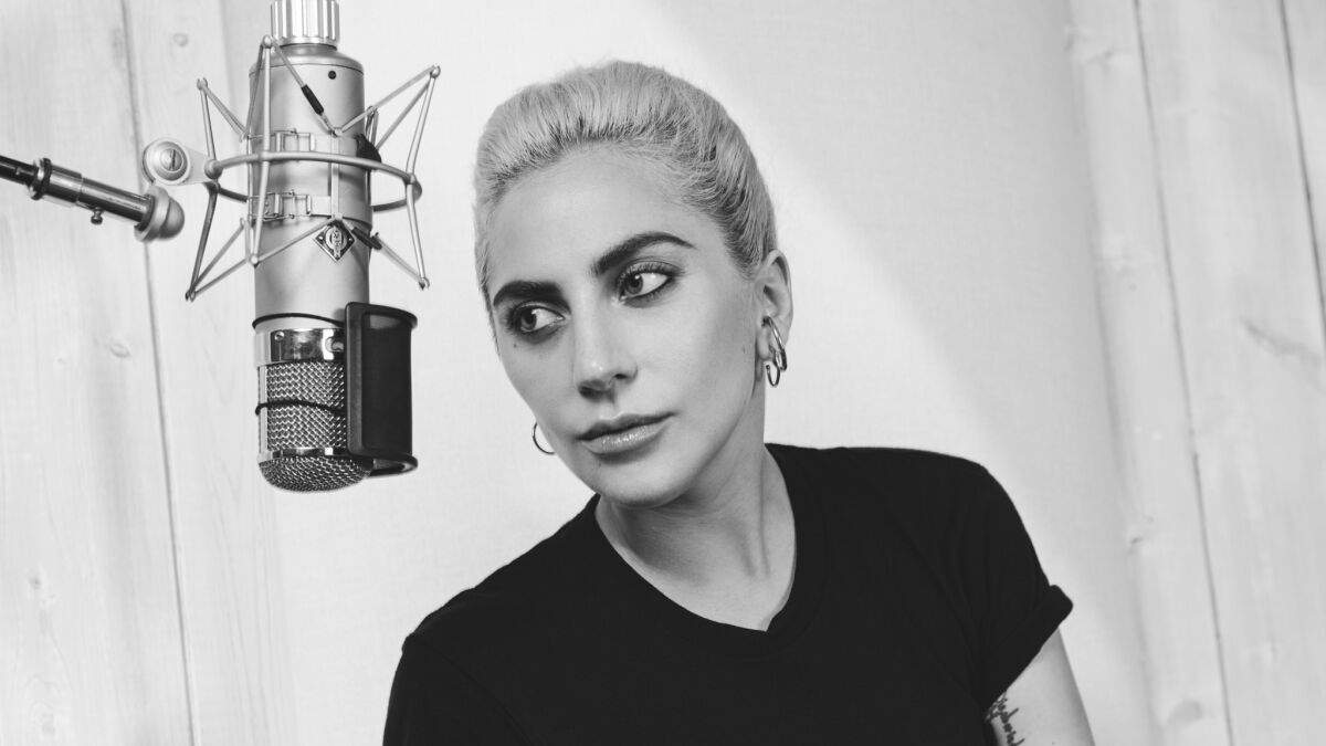 A black-and-white closeup of Lady Gaga behind a microphone.