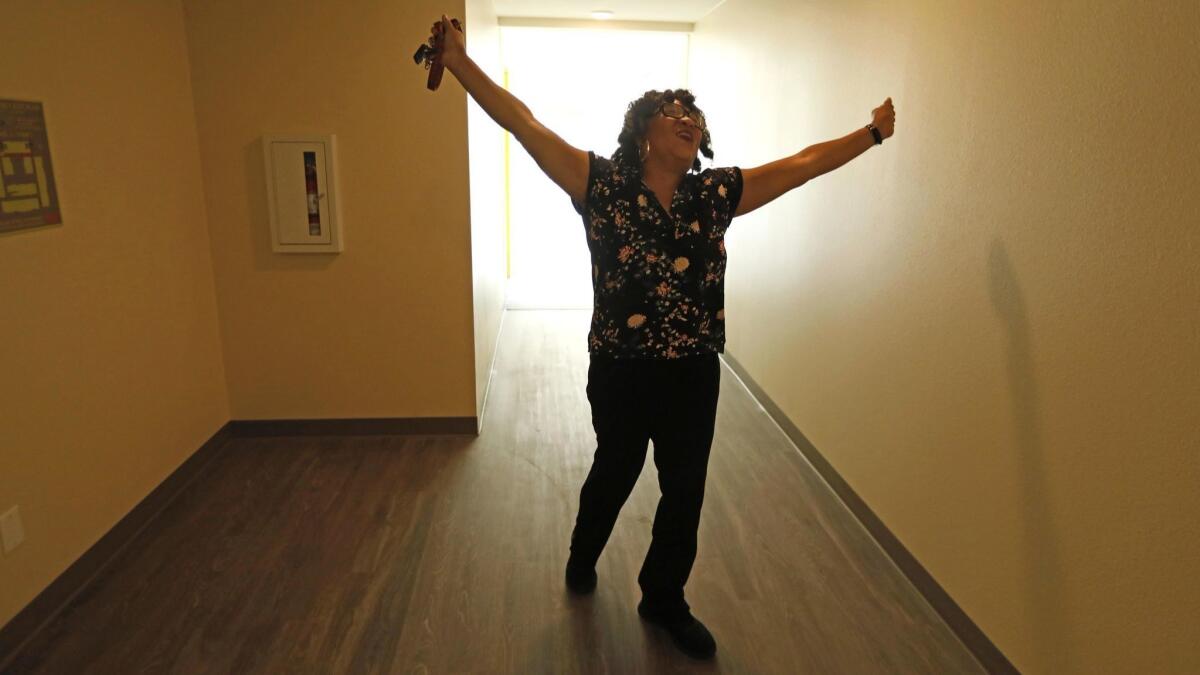 Carla McCue, 62, raises her arms after moving into her new apartment on Aug. 9, 2018.