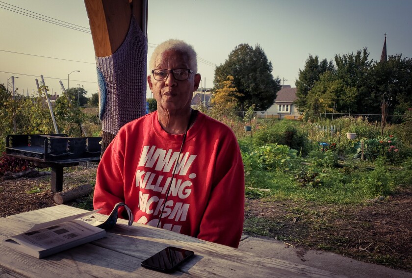 Anthony Courtney sits at a wood table in a community garden.