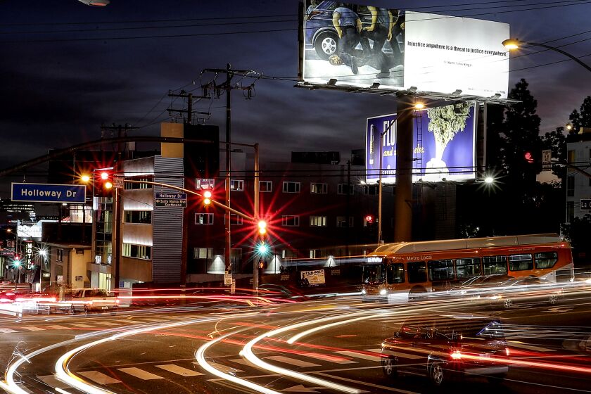 WEST HOLLYWOOD, CA. - JAN. 7, 2021. Motor traffic streams through the intersection of La Cienega Boulevard and Holloway Drive in West Hollywood beneath a billboard depicting the death by cop of George Floyd. (Luis Sinco/Los Angeles Times)