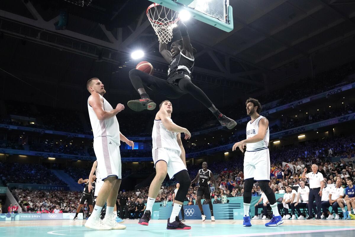 South Sudan's Wenyen Gabriel dunks as Serbia's Nikola Jokic, left, Nikola Jovic and Vasilije Micic defend 