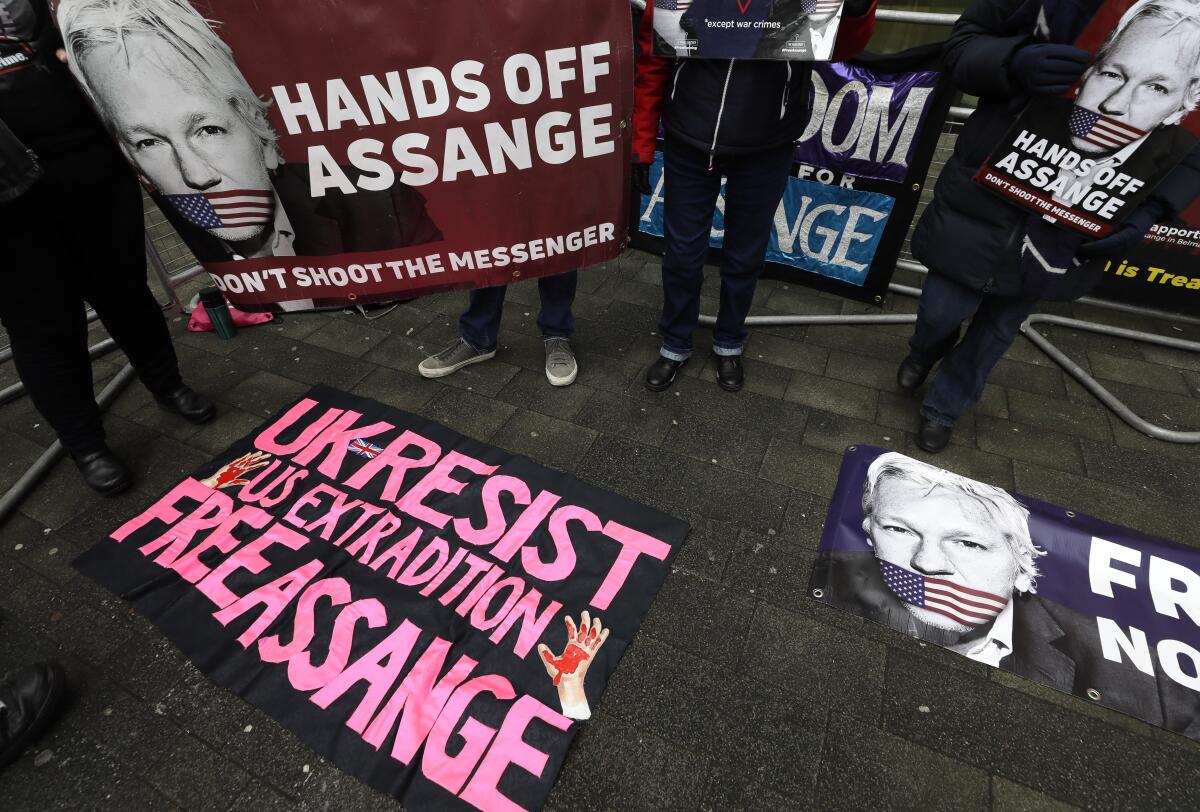 People hold posters reading "Hands Off Assange - Don't Shoot the Messenger" and "Free Assange."