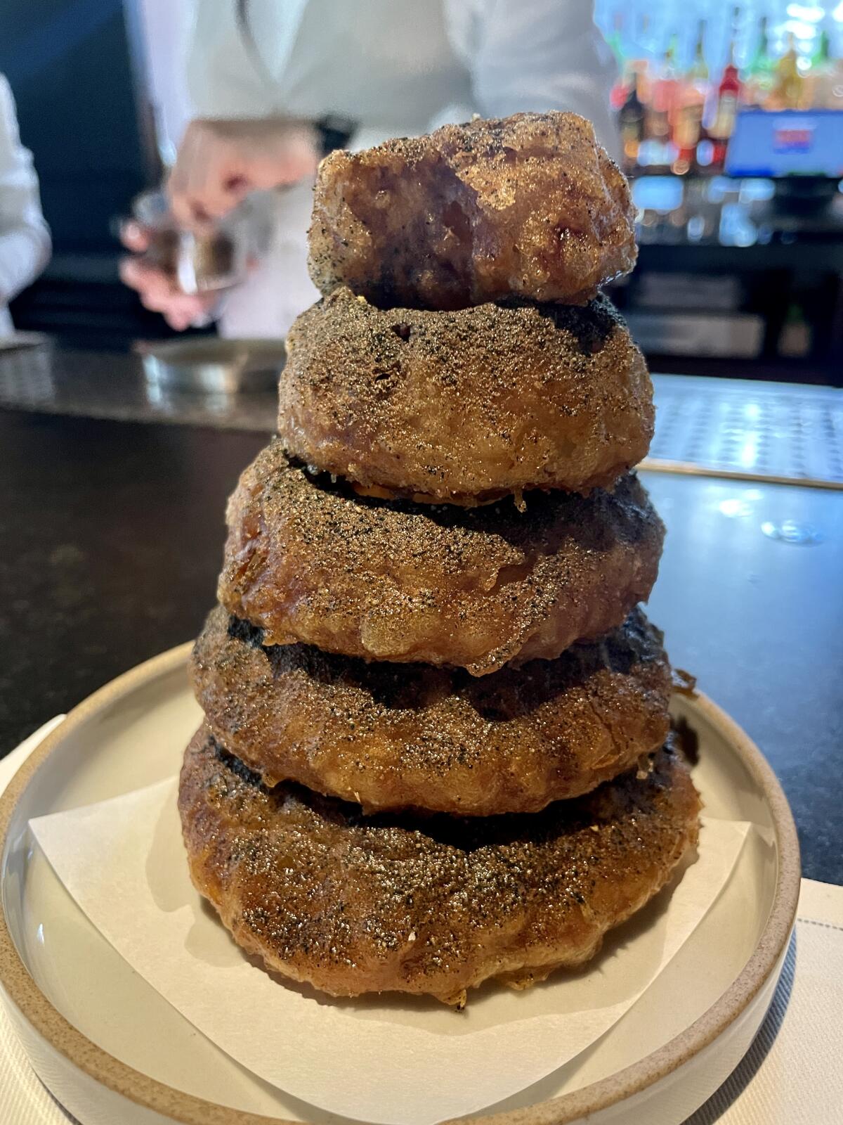 A thick stack of onion rings on a plate.