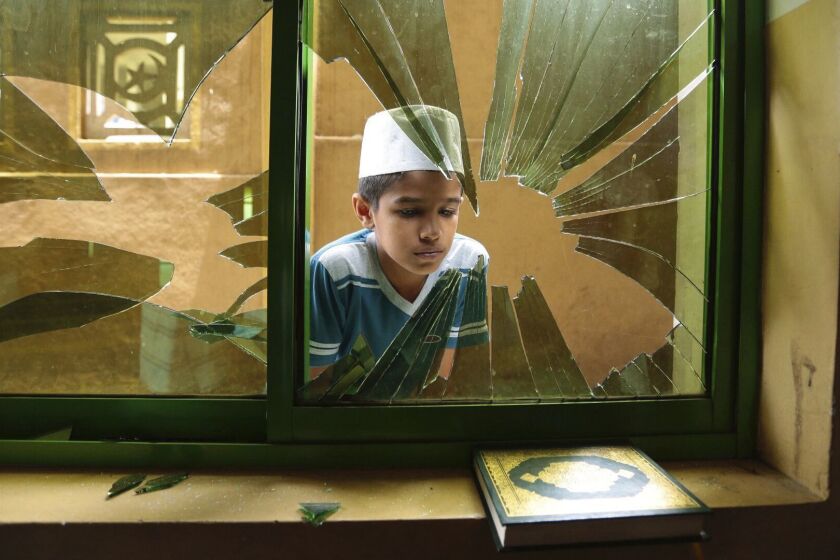 A Sri Lankan Muslim boy peeps through a broken window of a vandalized Mosque in Diana, Kandy, Sri Lanka, Friday, March 9, 2018. Calm was beginning to return to violence-hit Muslim neighborhoods in Sri Lanka's Kandy region on Friday, with many shops reopening as army reinforcements largely put an end to Buddhist mob attacks that hit the area. (AP Photo/Tharaka Basnayaka)