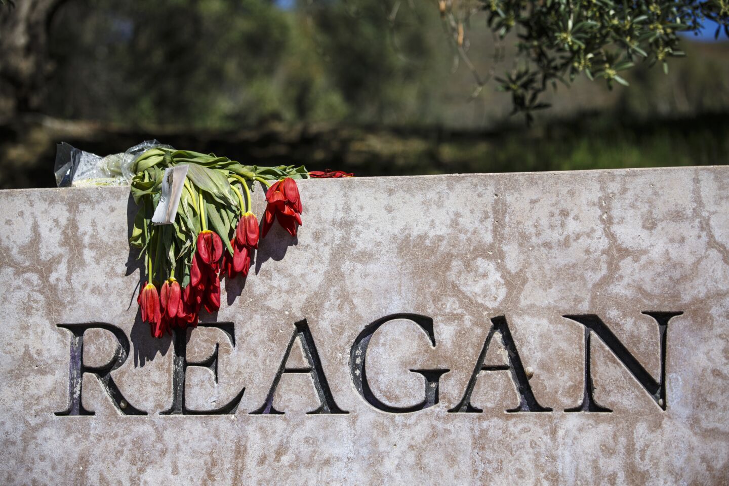 Flowers are placed at the entrance to the Ronald Reagan Presidential Library as people wait for the motorcade bringing Nancy Reagan's body to lie in repose.